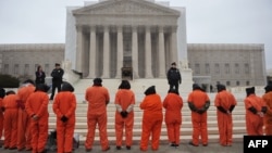 Участники акции протеста, одетые в тюремную робу, выступают перед зданием Верховного суда США с требованием закрыть тюрьму Гуантанамо. Вашингтон, 11 января 2013 года.