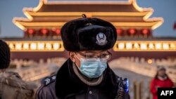 افسر پلیس چین در حالی که ماسک به صورت زده در نزدیکی میدان تیان‌آنمن در پکن