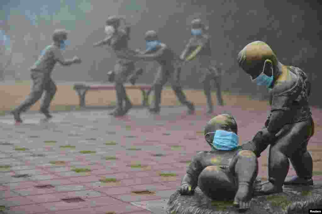 Masks are pictured on sculptures in a park during a hazy day in Puyang, Henan Province, China. (Reuters)