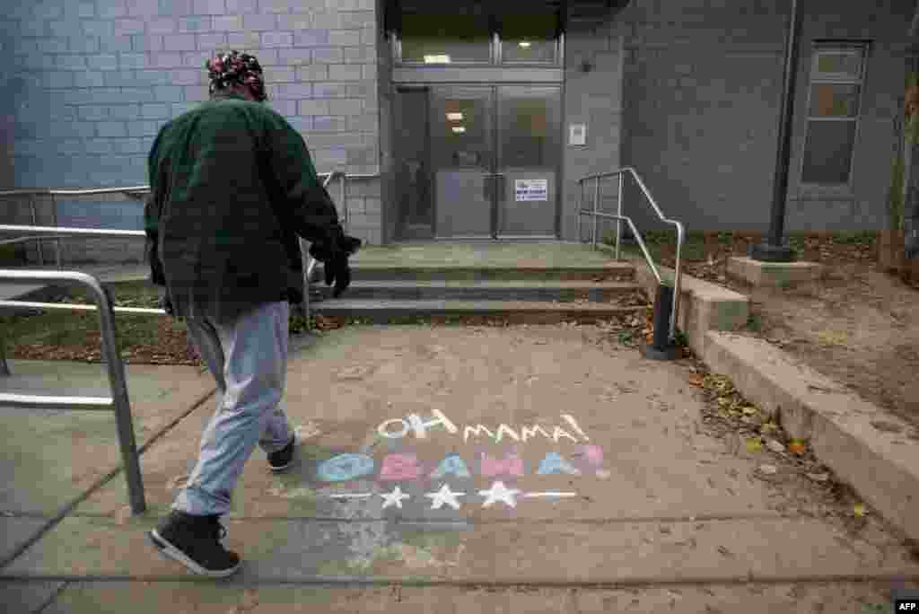A resident steps over chalk drawings in support of President Barack Obama as he enters a recreation center to vote in South Philadelphia, Pennsylvania.