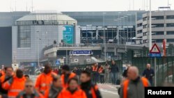 Люди покидают здание аэропорта в Брюсселе, где утром 22 марта 2016 произошли два взрыва 