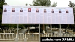 Түркіменстан президенттігіне кандидат 9 адамның сайлау плакаттары ілінген жарнама.