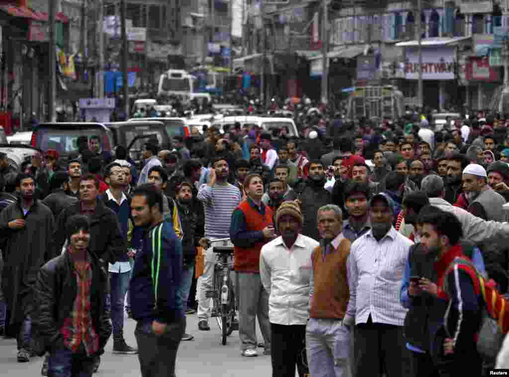 People stand on a road after vacating buildings in Srinagar.