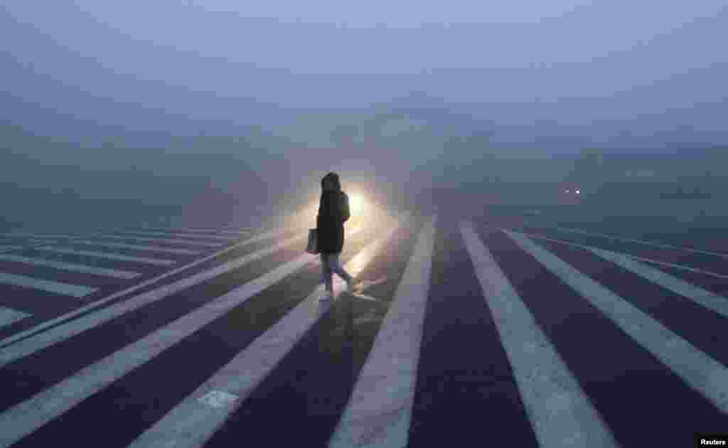 A Chinese woman walks along a street during a smog-filled day in Changchun, Jilin Province on October 22. Severe smog continues to shroud major cities in the northeast of the country. (Reuters/China Daily)