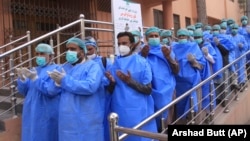 FILE: Hospital staff pray before begging their work shift outside a hospital for coronavirus infected patients in the southwestern city of Quetta on March 26.