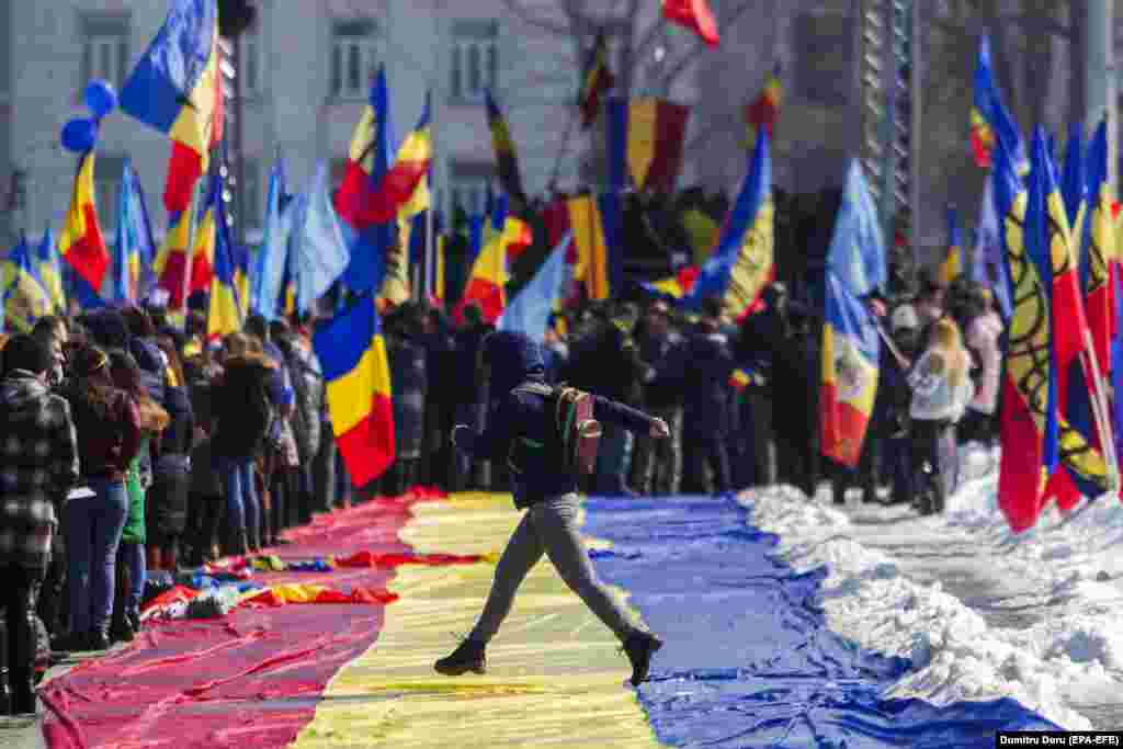 A girl jumps across a large Romanian flag during a rally ahead of the 100th anniversary of the unification of Bessarabia and Romania in central Chisinau, Moldova, on March 25. (EPA-EFE/Dumitru Doru)