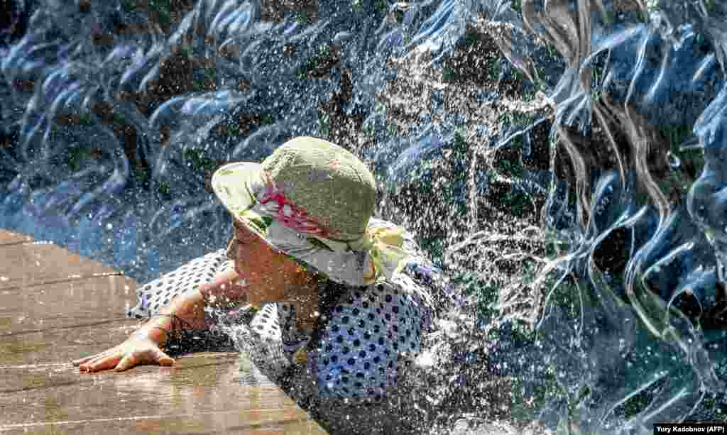 A girl cools off in a fountain in Manezhnaya Square on a warm summer day in downtown Moscow. (AFP/Yuri Kadobnov)