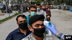 A health worker checks the body temperature of worshippers as a preventive measure against the COVID-19 before the Friday prayers on the first day of the Muslim holy month of Ramadan at Wazir Akbar Khan mosque in Kabul on April 24.