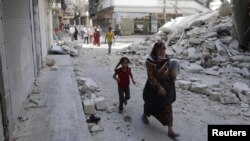 Syria -- Civilians walk near a destroyed building after a Syrian Air Force fighter jet launched a bomb in the city of Aleppo, 03Sep2012