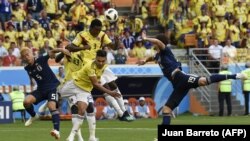 Players are shown in a match between the Colombian and Japanese soccer teams at the World Cup.