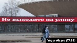 Мужчина и женщина гуляют возле надписи при входе в Казанский цирк. 31 марта 2020 года. 
