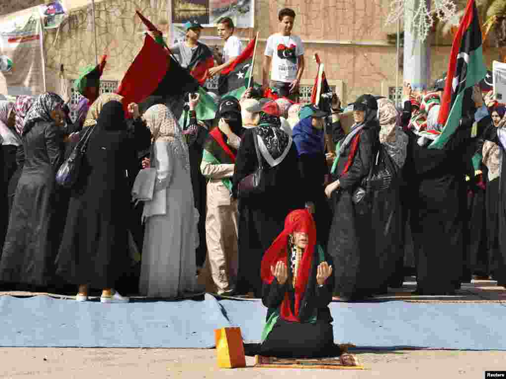 A woman prays as others celebrate the death of former Libyan leader Muammar Qaddafi after Friday Prayers on Martyrs' Square in Tripoli, Libya. (Suhaib Salem for Reuters)