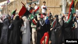 A woman prays at Martyrs Square in Tripoli as others celebrate the death of former Libyan leader Muammar Qaddafi after Friday prayers on October 21.