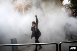 An Iranian woman raises her fist amid the smoke of tear gas during a protest at Tehran University on December 30.