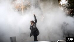 An Iranian woman raises her fist amid the smoke of tear gas at the University of Tehran during a protest driven by anger over economic problems, in the capital Tehran on December 30, 2017.