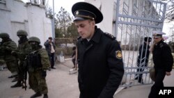 Ukrainian officers depart while Russian soldiers stand guard after they took control of a Ukrainian navy base in Novoozerny, Crimea, on March 19.