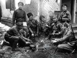 Red Army fighters gather for lunch around a fire in 1919.