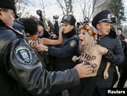 Polițiști ucraineni arestând astăzi o manifestantă Femen în fața parlamentului din Kiev.