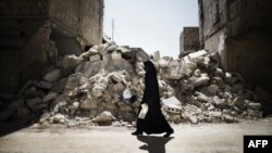 A Syrian woman walks past a destroyed building while walking to a food-distribution center in Aleppo.