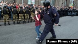 A Russian riot police officer detains a teenager during pension protests in St. Petersburg on September 9.