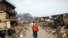 Japan -- A man covers his face as he walks through a destroyed residential area of tsunami-hit Otsuchi, 14Mar2011