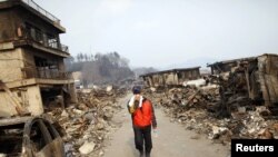 Japan -- A man covers his face as he walks through a destroyed residential area of tsunami-hit Otsuchi, 14Mar2011