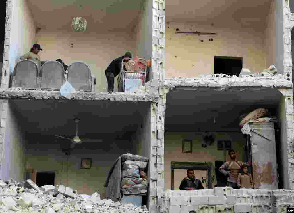 Жыхары сырыйскага гораду Алепа глядзяць з разбуранага будынку пасьля бамбаваньня, як мяркуецца, урадавымі сіламі 7 сьнежня. (AFP/Karam al-Masri)