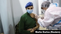 Медицинска сестра в Белград поставя китайска ваксина на офицер от армията.