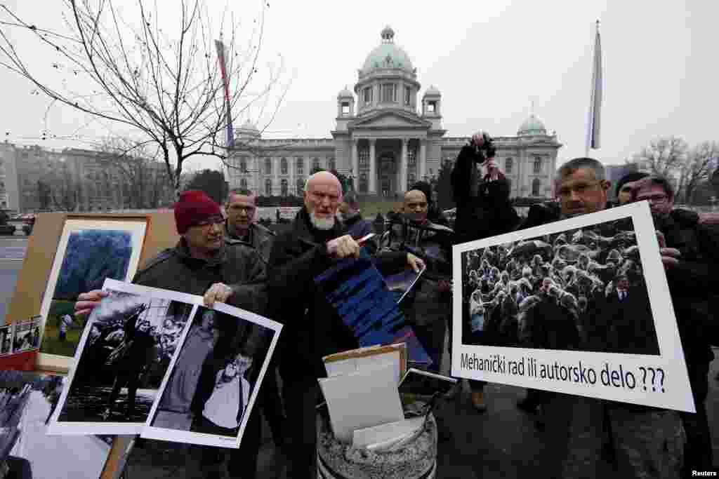 Fotoreporter Dragoljub Zamurović (u sredini) uništava svoju fotografiju na protestu ispred Skupštine Srbije. &ldquo;Mehanički rad, ili autorsko djelo?&rdquo; - pitalo je stotinak fotoreportera poslanike u danu kada glasaju o zakonu koji prijeti da naruši njihova autorska prava. (Reuters/Marko Djurica)