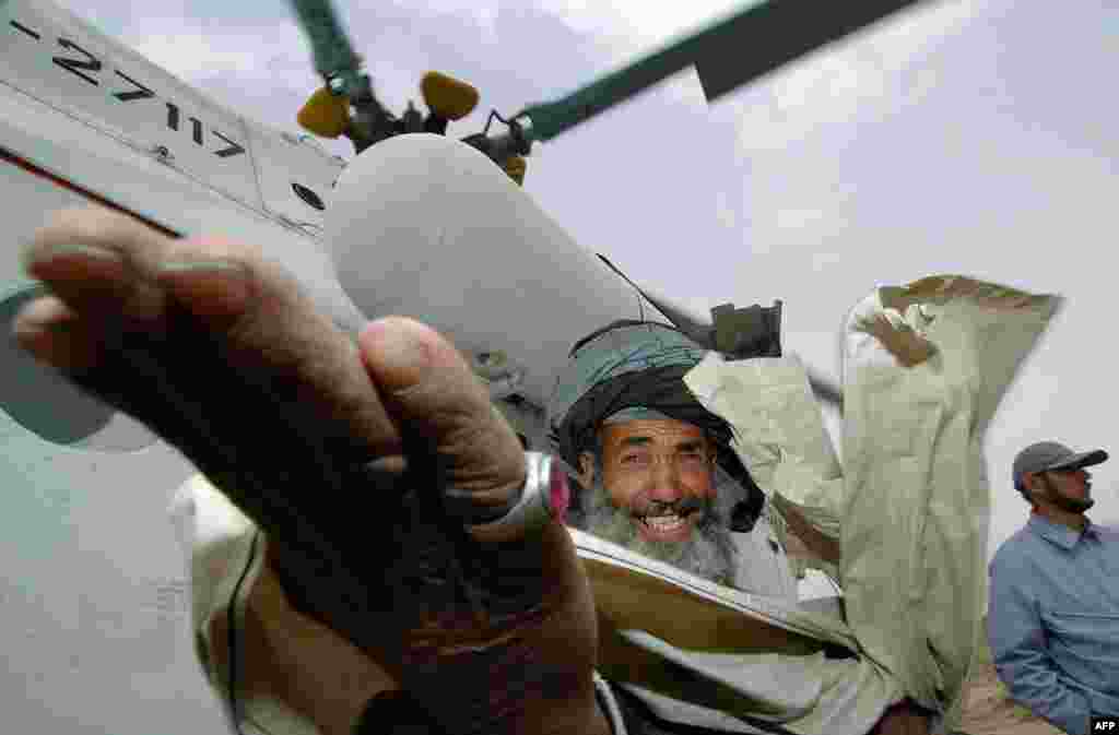 A villager smiles while welcoming a UN helicopter landing to collect ballot boxes in a remote eastern village on October 10, 2004, the day after the first direct presidential election in Afghan history.