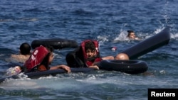 Refugees float as they hold a tube after a dinghy carrying Syrian and Afghan refugees deflated some 100 meters from the Greek island of Lesbos in September 13.