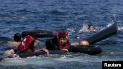 FILE: Refugees float as they hold a tube after a dinghy carrying Syrian and Afghan refugees deflated some 100m away before reaching the Greek Island of Lesbos in September 2015.