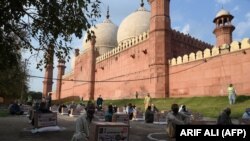People in need sit maintaining social distancing after collecting free food items outside the Badshahi mosque in the eastern city of Lahore on April 21.
