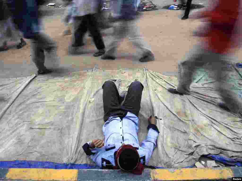 An Yemeni antigovernment demonstrator rests on a street occupied by protesters after clashes with security forces in Sanaa on September 19. (Photo taken by Khaled Abdullah for Reuters)