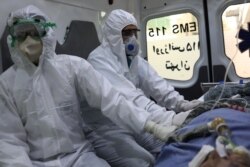 Сотрудники скорой помощи в защитных костюмах сидят во время транспортировки пациента с коронавирусной инфекцией. Иран, 30 марта 2020 года.