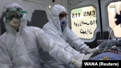 Emergency medical staff wearing protective suits, sit in an ambulance while transferring a patient with coronavirus (COVID-19) to Masih Daneshvari Hospital, in Tehran, March 30, 2020