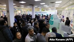 Iranians wait to get medication and masks at the state-run "13 Aban" pharmacy in Tehran, February 19, 2020