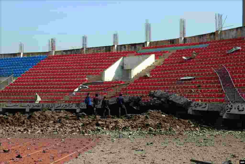 People inspect damage caused by a suspected air strike conducted by the Saudi-led alliance that hit houses and a stadium in Ibb, Yemen. Saudi Arabia is leading a coalition of several Arab countries that are carrying out strikes against Huthi rebels. (epa)