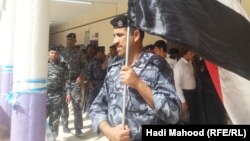 رجل أمن عراقي يرفع علم بلاده أثناء عملية التصويت الخاص في الإنتخابات البرلمانية