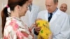 Vladimir Putin Kalininqraddakı doğum evini ziyarət edərkən yeni doğulmuş uşağı qucağında tutur