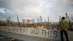 Lebanon -- A man stands next to graffiti at the damaged port area in the aftermath of a massive explosion in Beirut, August 11, 2020.