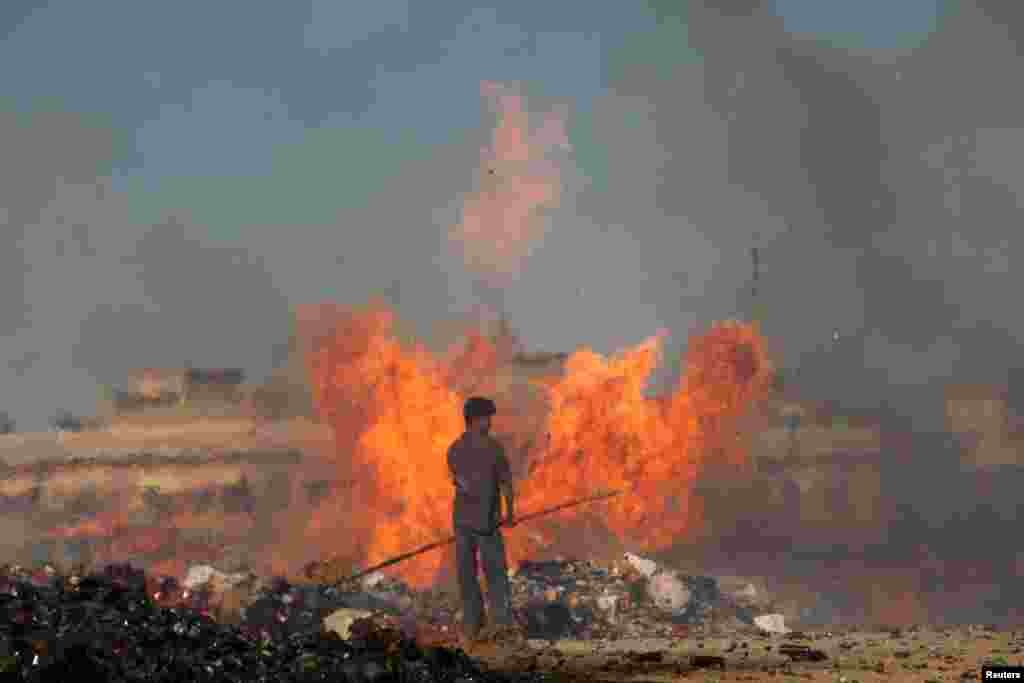 A Pakistani customs employee stands amid burning piles of confiscated contraband and narcotics destroyed during a campaign marking International Customs Day in Karachi on January 26. (Reuters/Akhtar Soomro)