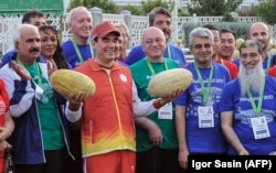 Президент Туркменистана Гурбангулы Бердымухамедов в окружении официальных лиц и участников предстоящих в 2017 году Азиатских игр в закрытых помещениях и по боевым искусствам позирует с дынями во время празднования Дня дыни в Ашхабаде, 18 августа 2017 года