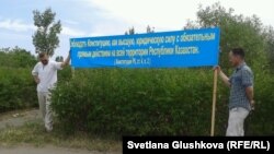 Жерлерінен айыруға қарсы тұрғындар Конституциядан үзінді жазылған баннер ұстап тұр. Астана, 28 маусым 2014 жыл. (Көрнекі сурет.)