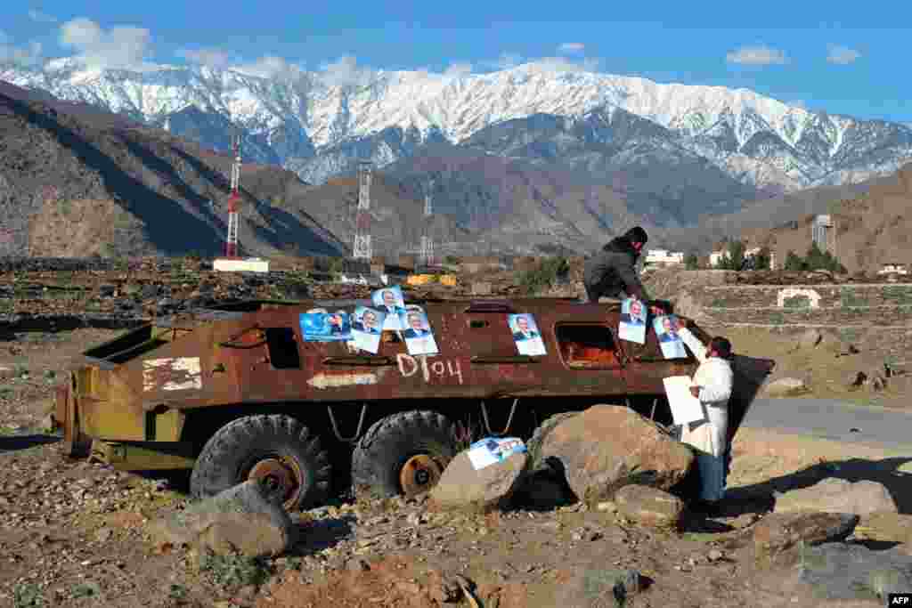 Workers paste election campaign posters of presidential candidate Zalmay Rasul onto the rusted remains of a Soviet-era armored personnel carrier on the outskirts of Jalalabad in Nangarhar Province. (AFP/Noorullah Shirzada)