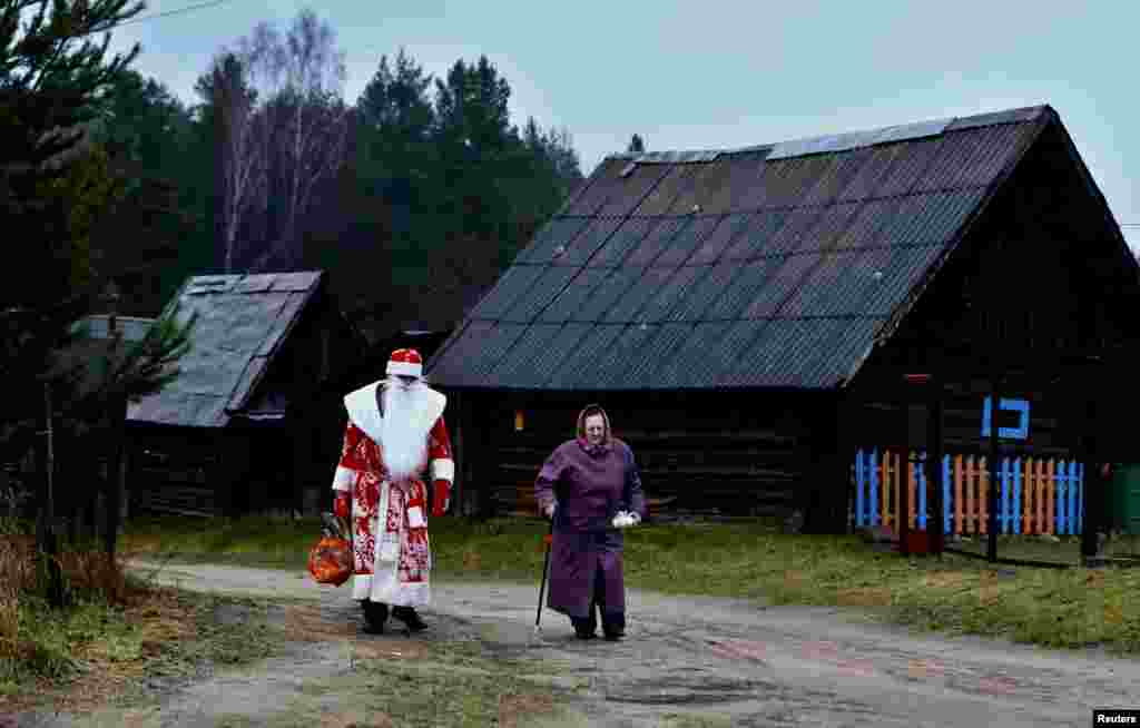 A driver of a mobile shop, dressed as &quot;Father Frost&quot; (a Slavic equivalent of Santa Claus), helps a woman carry products that she bought on the outskirts of Minsk, Belarus, on December 23. (Reuters/Vasily Fedosenko)