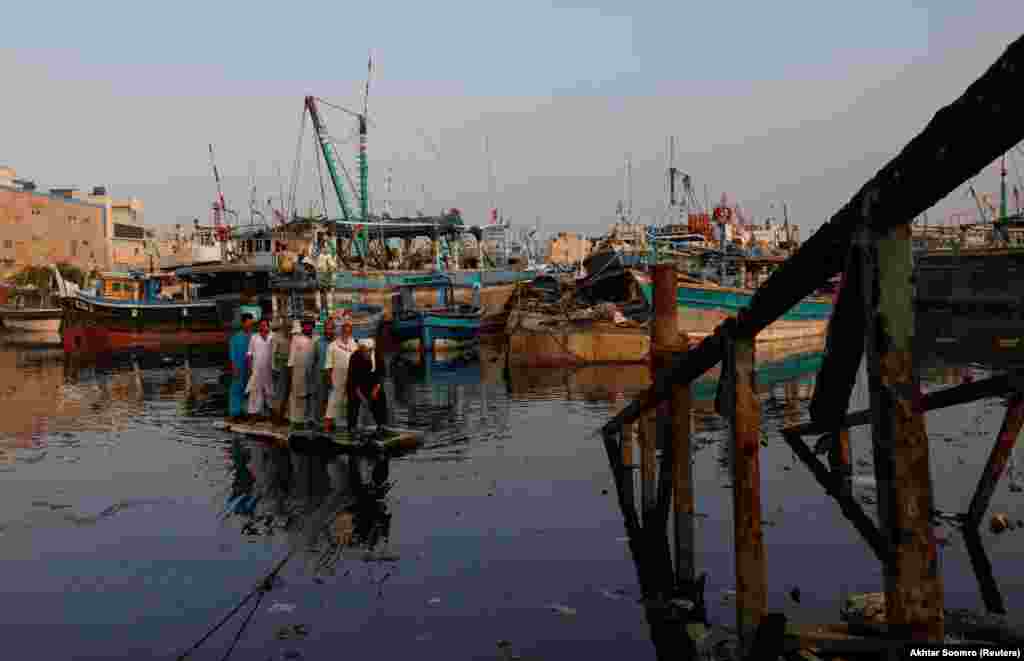 Fishermen sail on an improvised raft with anchored fishing boats in the background as they cross Fish Harbor in Karachi, Pakistan. (Reuters/Akhtar Soomro)