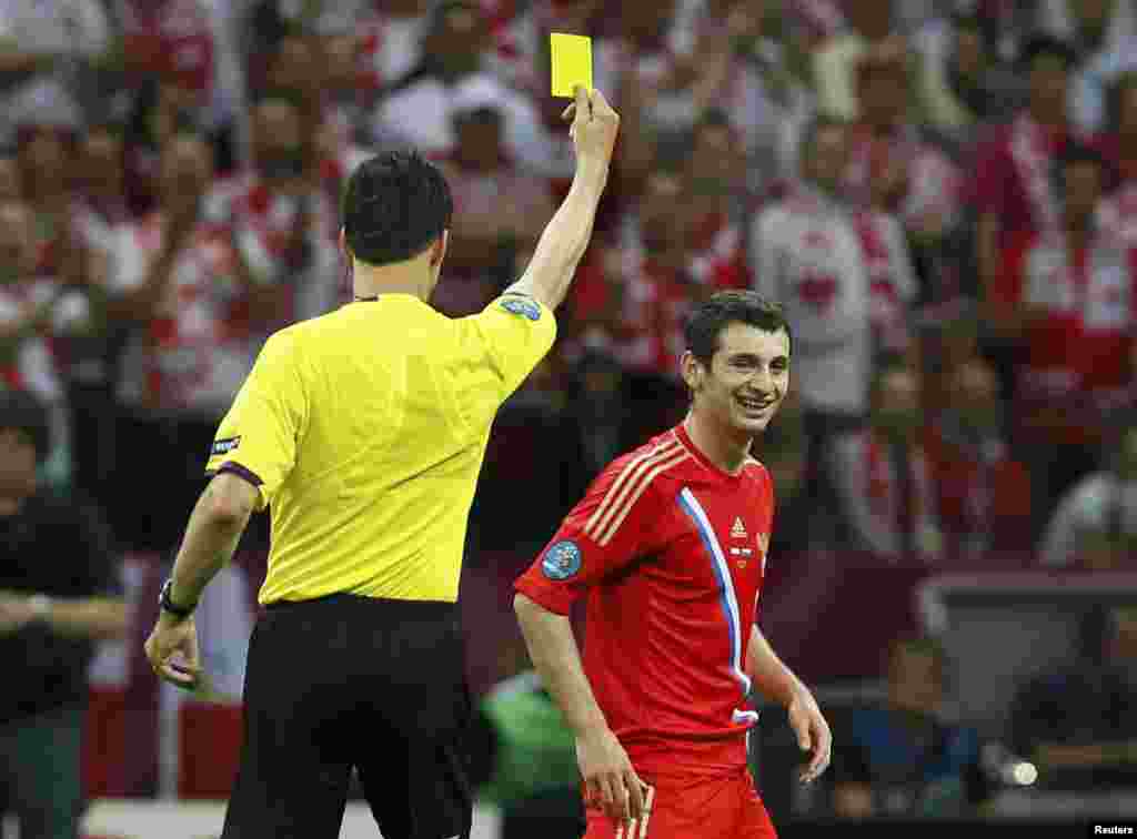 Russia&#39;s Alan Dzagoev (right) reacts as referee Wolfgang Stark of Germany shows him the yellow card during the match against Poland in Warsaw.