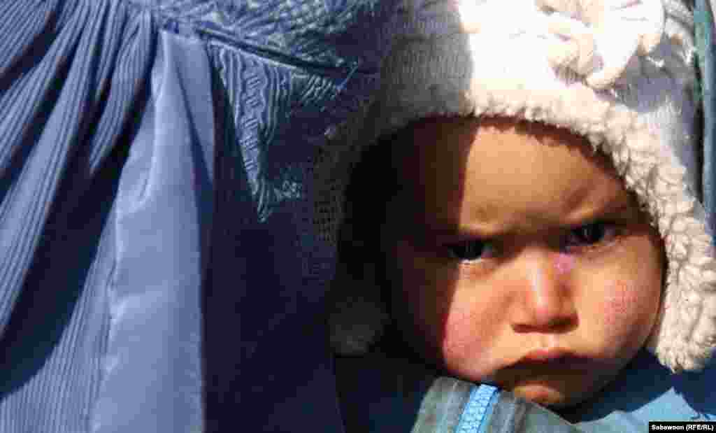 An Afghan woman holds her child as she waits to receive winter aid supplies in Kabul. (RFE/RL/Sabawoon)