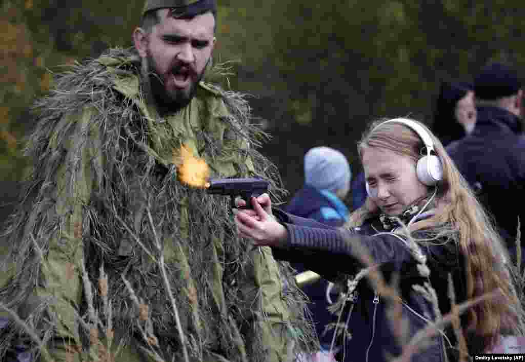 A girl shoots a gun loaded with blanks at an weapons exhibition during a military show in St. Petersburg. (AP/Dmitry Lovetsky)